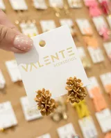 Aros tipo caravana en tono tostado, con diseño floral tridimensional adornado con pequeñas cuentas doradas en el centro.