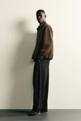 Pantalón de corte balloon fit confeccionado en tejido con viscosa. Presenta cintura ajustable con cinturón integrado, pliegues frontales, bolsillos laterales y bolsillos traseros de doble vivo. Cierre frontal con cremallera y botón.