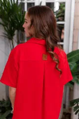 Vestido camisero de muselina color negro, de largo midi, con cuello clásico, manga corta y cierre frontal con botones.