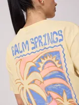 Remera color salmón de corte holgado, con estampado pequeño en el frente que incluye un arcoíris y el texto "Rusty Club".