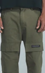 Pantalón cargo de color verde militar, corte recto y holgado, con bolsillos cargo a la altura de los muslos y detalles de costuras reforzadas en las rodillas.