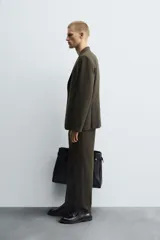 Blazer de corte slim fit en color verde oscuro, con cuello de solapas de muesca, cierre frontal de un botón, bolsillos laterales con solapa y bolsillo de vivo en el pecho.