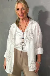 Camisa de seda color blanco crudo, con estampado en relieve bordado de hojas, cuello camisero, mangas largas y cierre frontal con botones.