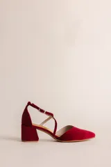 Zapato de tacón bajo color bordó, con punta en V, tiras cruzadas en el empeine y cierre de hebilla en el tobillo. Tiene un tacón ancho de 5 cm.
