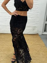 Pollera larga asimétrica confeccionada en encaje con detalles de terciopelo, con forro interno y cintura elástica.