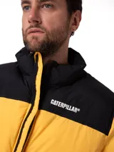 Campera puffer Caterpillar color amarillo y negro, con cuello alto, cierre frontal y bolsillos con cremallera. Presenta el logo de la marca estampado en el pecho.