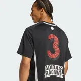 Camiseta de manga corta Adidas Teamgeist de color negro, con cuello redondo y diseño gráfico con estampas y patrocinadores deportivos en el pecho y las mangas. Presenta detalles en blanco y gris en los laterales.