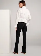 Pantalón de jean bootcut color negro con costuras en color naranja, tiro alto, pretina con trabillas, cierre frontal con cremallera y botón, y cinco bolsillos.