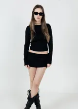 Camiseta negra de tejido texturizado, con cuello alto y mangas largas ajustadas.
