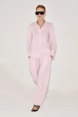 Pantalón de tiro medio confeccionado en 100% lino color rosado, con diseño de pernera ancha, pinzas en el delantero, cintura elástica en la parte posterior y bolsillos laterales. Cuenta con cierre frontal con cremallera y botón.