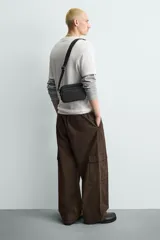 Bandolera negra rectangular de tela técnica con correa ajustable y extraíble.