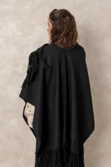 Ruana abierta de color beige, confeccionada en tejido de punto con terminación de flecos en el ruedo.