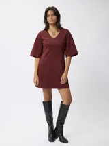 Vestido corto de gamuza sintética color bordó, con escote en V, mangas tres cuartos acampanadas y corte entallado en la cintura.