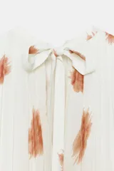 Vestido midi de viscosa color blanco con estampado abstracto marrón, diseño sin mangas, cuello redondo plisado y cierre de lazos en la espalda.