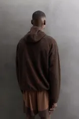 Sudadera regular fit confeccionada en tejido polar ligero con textura efecto pelo en color marrón y negro. Presenta cuello subido con capucha ajustada, manga larga ranglán, bajo asimétrico más largo en la espalda y acabados con cinta elástica.