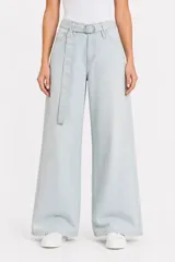Pantalón jean de tiro alto y corte ancho, color celeste claro, con bolsillos laterales y cinto de la misma tela con hebilla metálica circular doble.