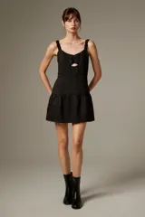 Vestido corto de poliéster color negro con estampado de lunares brillantes tipo strass, tirantes finos con volados, escote con abertura cut-out en el centro y falda con volado fruncido en el borde inferior.