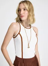 Musculosa blanca de punto con corte recto, cuello redondo, sisas amplias y vivo terracota en cuello y sisas.