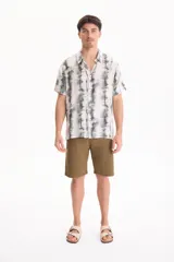 Camisa de manga corta con estampado tie-dye en tonos verdes y blancos, cuello cubano y cierre frontal con botones.