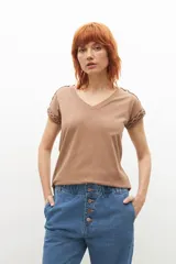 Remera negra de corte recto, con cuello en V y detalle de trenzas en los hombros.