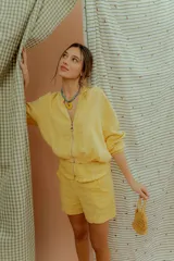 Campera tipo bomber de lino color amarillo, con cierre frontal metálico y mangas largas con puños elásticos.