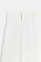 Bermuda de tiro medio color blanco, con trabillas en la cintura, bolsillos ocultos en las costuras delanteras, bolsillos de vivo en la espalda y detalle de nervio frontal. Cierre frontal con cremallera y ganchos metálicos.