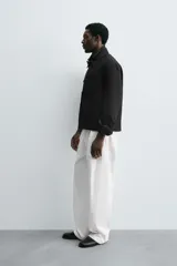 Sobrecamisa color beige de corte cuadrado, con cuello solapa, manga larga con puños abotonados, bolsillos laterales y cierre frontal con botones.