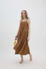 Vestido midi de lino color salmón, de corte amplio y silueta holgada. Presenta diseño con cortes irregulares y detalles de pasamanería en el escote y costuras. Cuenta con breteles dobles tipo cuerda y ruedo asimétrico.