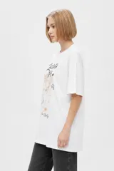 Remera blanca de algodón con cuello redondo, mangas cortas y calce holgado. Cuenta con un estampado frontal de estilo gráfico que dice "Negroni" junto con la ilustración de un trago y rodajas de naranja.
