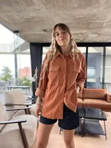Sobrecamisa color terracota de pana con cuello camisero, cierre frontal con botones, dos bolsillos con solapa en el pecho y mangas largas con puños abotonados.