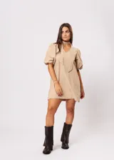 Vestido corto color beige, de corte oversize, con escote en V y mangas globo. Incluye cinturón marrón con hebilla dorada.