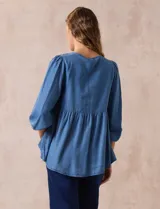 Blusa celeste de tencel y rayón, marca Marissa Olivia. Tiene cuello redondo, escote en V con aplique de crochet y lazo de ajuste. Corte en cintura y espalda. Manga larga amplia con puño elastizado.