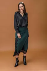 Falda midi de satén en color verde oscuro, con corte irregular y detalle de encaje negro en el ruedo y en uno de los laterales.