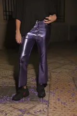 Pantalón de ecocuero color violeta metalizado, con corte capri semi oxford y tiro medio-alto. Presenta cierre frontal con botón metálico y bolsillos traseros.