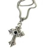 Collar plateado con dije de cruz ornamentada con detalle de piedra negra en el centro.