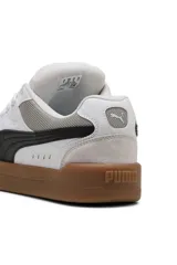 Championes Puma modelo Park Lifestyle Sk8, de diseño urbano inspirados en el skate, color blanco con franja lateral negra, detalles en gamuza gris en la puntera y suela de goma marrón tipo gum.