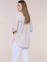 Camisa de calce relajado color celeste, confeccionada en tejido de textura suave y fluida. Presenta cuello camisero y abotonadura frontal, mangas largas con puño ancho y ruedo curvo.