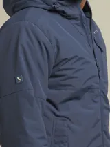 Campera negra con capucha, cierre frontal y bolsillos laterales con botón a presión.