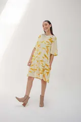 Vestido corto acampanado color crema con estampado de hojas amarillas, cuello redondo y mangas cortas.