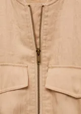 Chaqueta tipo bomber color beige, con cierre frontal de cremallera, cuello redondo, bolsillos de solapa en el pecho y cintura y puños elásticos.
