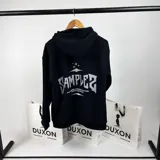 Canguro negro oversize con capucha y cordones ajustables. Estampa en la espalda con el texto "SAMPLER THE MINIMAL GARMENTS FACTORY DUXON INDUSTRIES" en color gris.