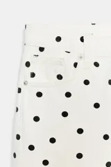Jeans de tiro bajo con diseño de pierna ancha y corte largo. Presenta un estampado de lunares negros sobre fondo blanco, cierre frontal con cremallera y botón metálico, y cinco bolsillos.