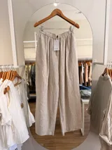 Pantalón palazzo de lino color beige, de corte amplio y relajado, con cintura elástica fruncida y botón frontal.