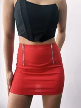 Minifalda roja ajustada con dos cierres metálicos decorativos en el frente.