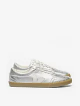 Championes Veja modelo Volley, con acabado metalizado plateado, suela de goma color caramelo y detalle de la V lateral en color blanco.