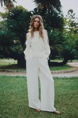 Blusa de cuello redondo y manga larga acabada en puño con frunces, detalle de aberturas en las mangas, frunces laterales y cierre trasero con abertura y botón.