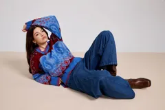 Sweater de tejido de punto con diseño estampado tipo paisley y floral en tonos azul, rojo y bordó. Presenta un cuello polo con escote en V, mangas largas y un corte holgado.
