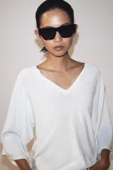 Top de punto fluido color negro, con escote en V y mangas cortas amplias.
