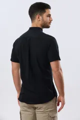 Camisa de lino y algodón de manga corta, color negro, con cuello mao, cierre frontal con botones y bolsillo ojal en el pecho.