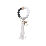 Llavero con pulsera de cuentas redondas de silicona en tonos celeste y gris, con un cubo de madera natural y borla decorativa en color celeste.